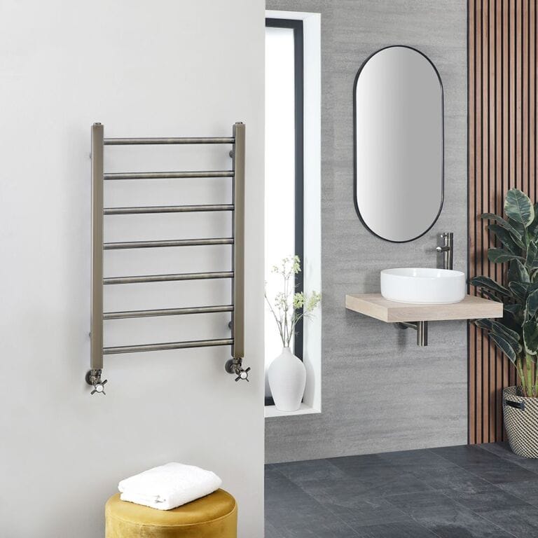 Milano Ezra dark gold stainless steel heated towel rail on white wall in modern bathroom setting