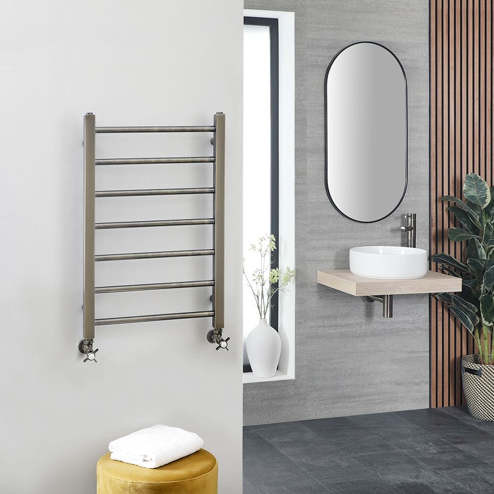 Milano Ezra dark gold stainless steel heated towel rail on white wall in modern bathroom setting