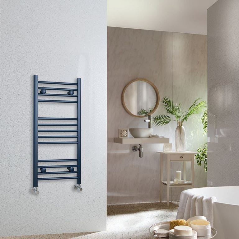 Milano Ive regal blue straight heated towel rail on white wall in modern bathroom with mirror and sink and bathtub