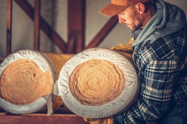 a workman holding a roll of insulation