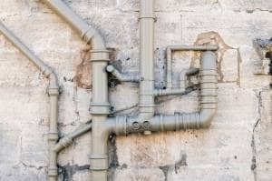 Galvanized steel heating pipes on dilapidated exterior wall