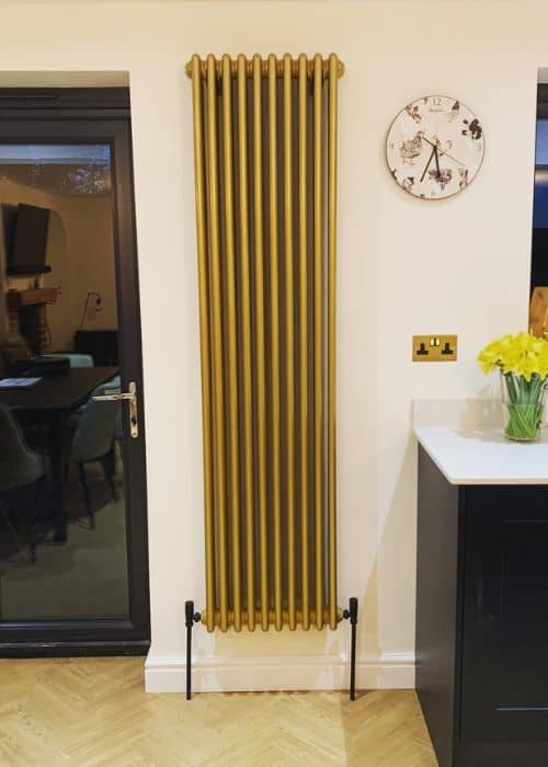 vertical gold column radiator in a white kitchen