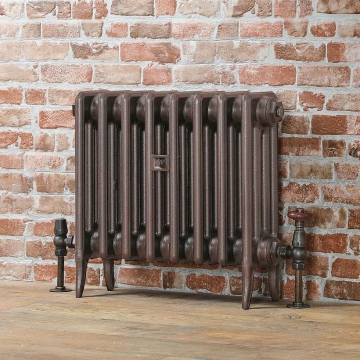 Traditional column radiator Traditional bronze low level radiator on brick effect wall