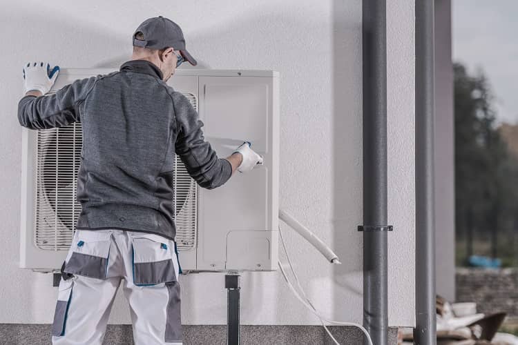 man installing an air source heat pump for energy efficient heating