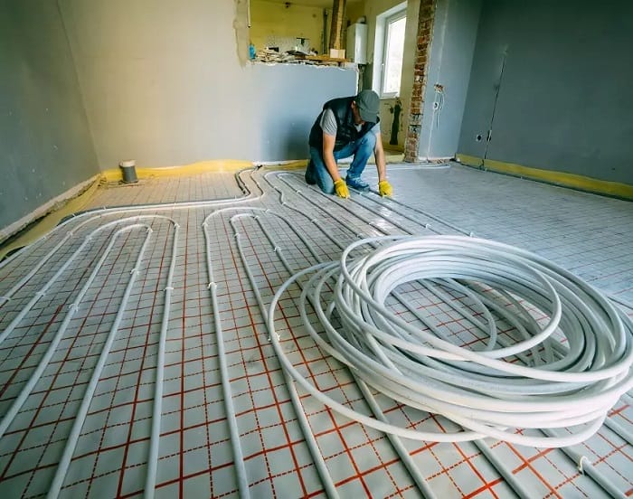 Heating engineer with electric underfloor heating wires Heating engineer laying electric underfloor heating wiring for installation