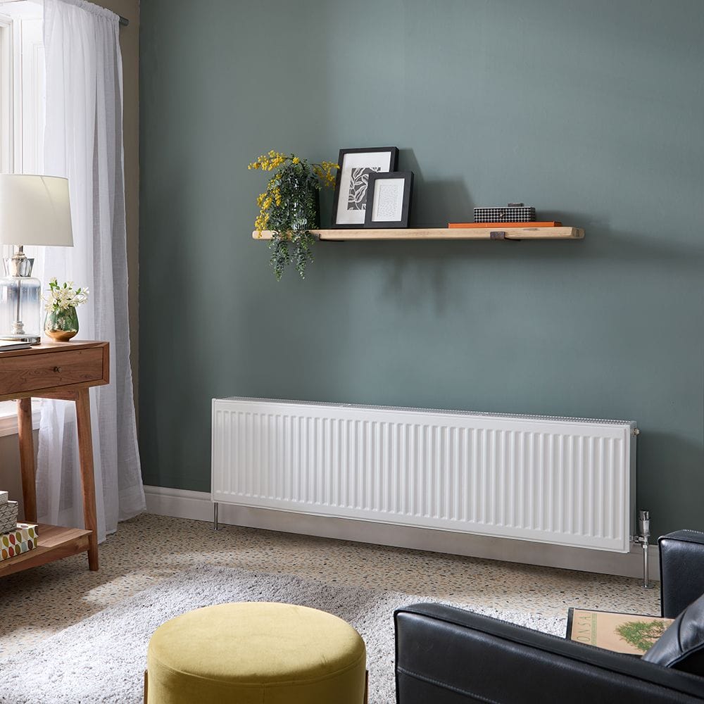 Milano Compact white Type 33 low level triple panel convector radiator on green wall beneath shelf