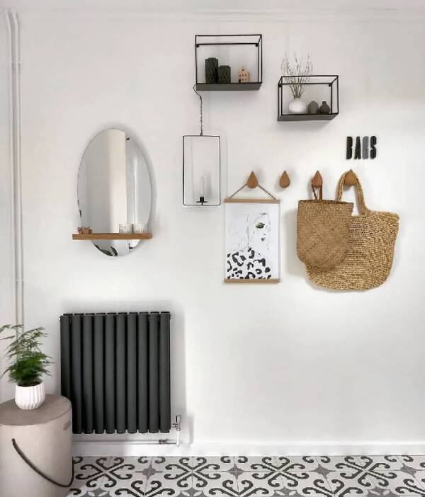 Milano anthracite vertical radiator on white wall with mirror and accessories A Milano Aruba anthracite radiator on a white wall beneath a mirror and other hanging accessories