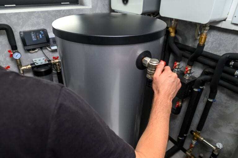 Modern grey and black boiler in boiler space being adjusted by hand