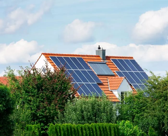 House with solar panel rooftop House behind trees featuring black solar panels on a red tiled roof