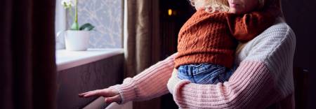 mother holding a child next to a radiator
