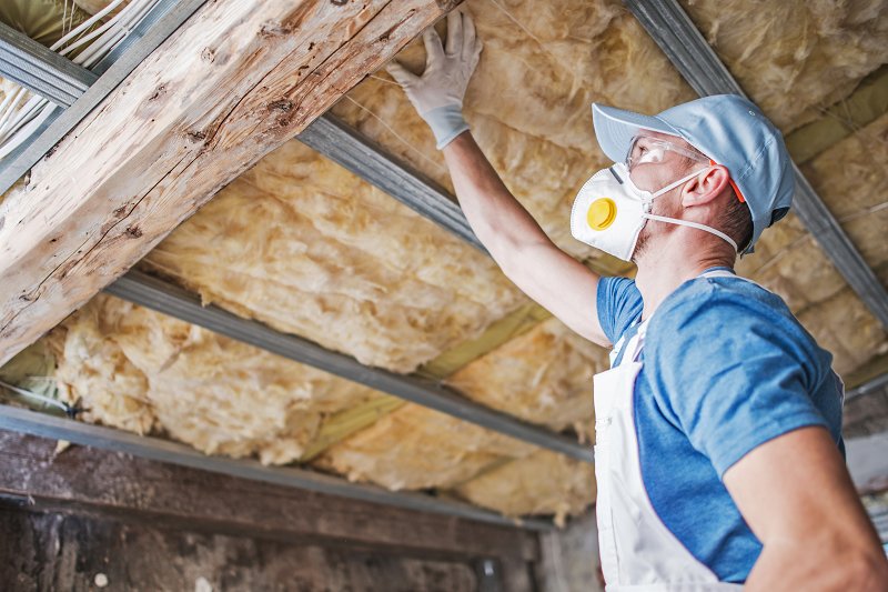 old-roof-insulation-MTWYCKQ a workman inspecting roof insulation