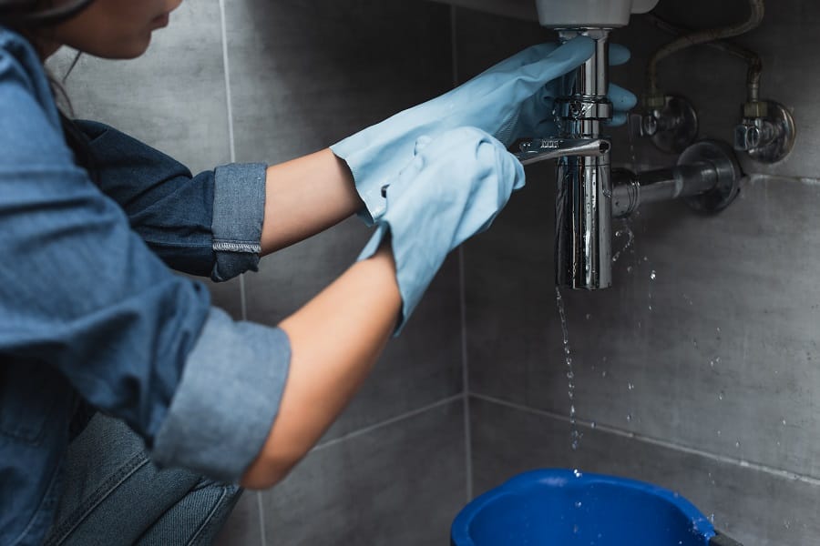 Woman repairing pipe with spanner Woman with blue rubber gloves repairing pipe with spanner
