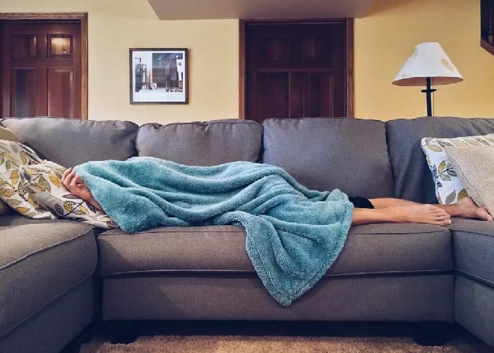 Lying down on the sofa A person lying under a blanket on a settee