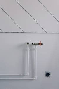 Feed and return heating pipes White feed and return heating pipework on white wall