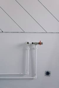 White feed and return heating pipework on white wall