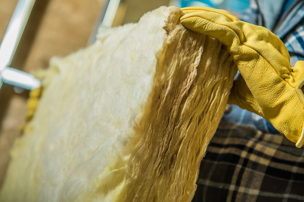 Mineral wool insulation material handled by installer in yellow leather gloves