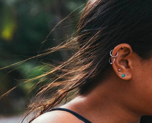 Close up of woman’s ear with multiple earrings and ear piercings