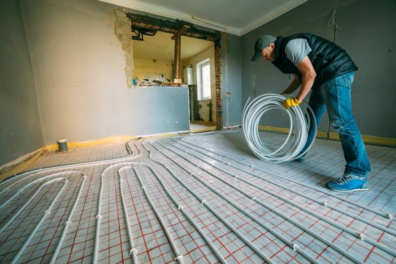 Plumber setting up wiring for electric underfloor heating installation