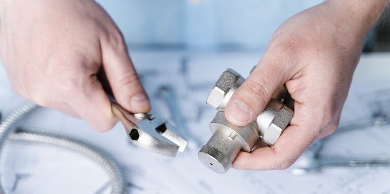 Hands holding spanner and valve for adjustment in home plumbing project