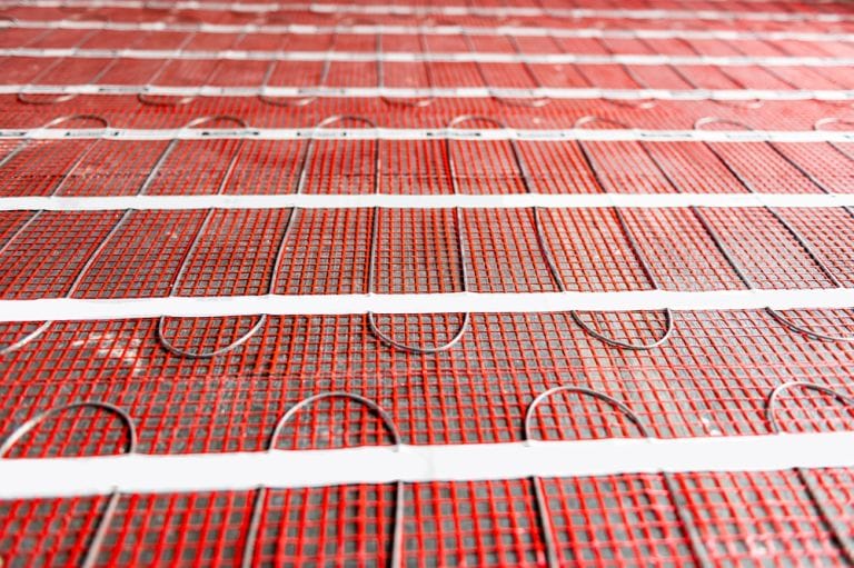 Electric underfloor heating mats on concrete floor in the form of radiant heating cable attached to fiberglass mesh