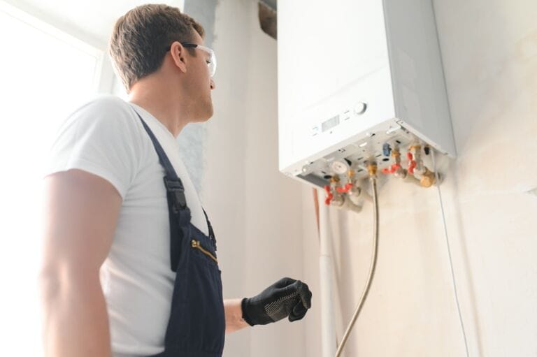 Professional plumber wearing safety goggles checking a boiler and pipes