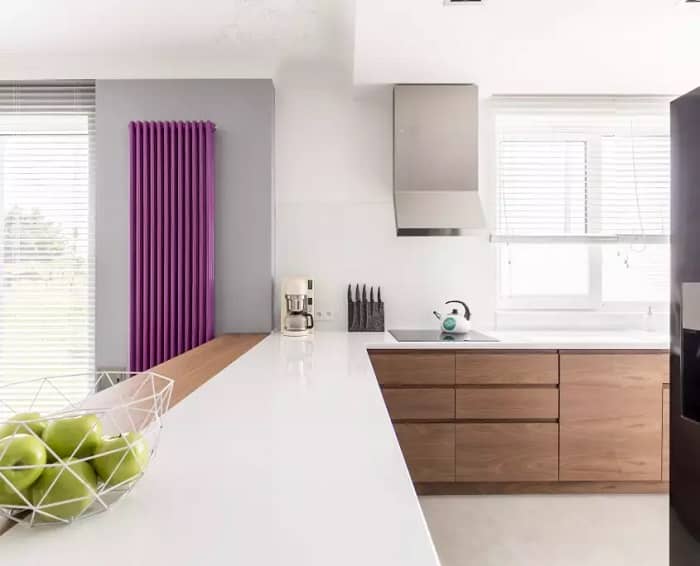 an unusual pink radiator in a white kitchen space