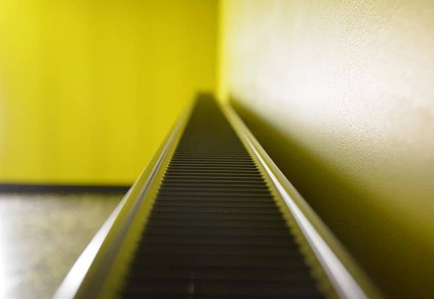 Close up shot of fins on top of a convector radiator with yellow wall in background
