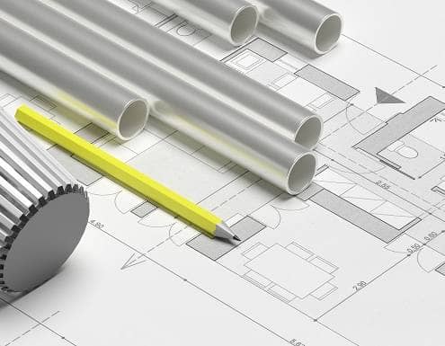 Radiator valve, yellow pencil and multiple aluminium heating pipes on building blueprint plans