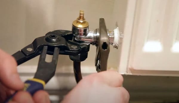 a man removing a radiator valve to replace a radiator