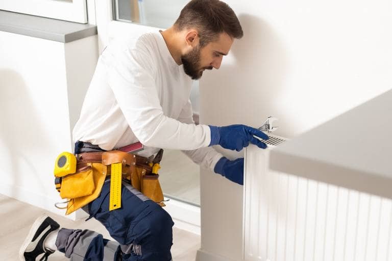 Heating professional repairing radiator using spanner