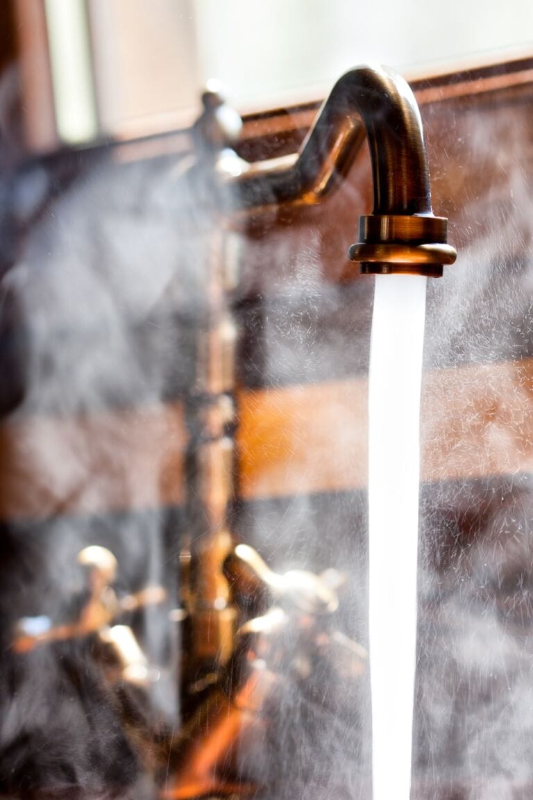 Hot water running out of a vintage tall bronze tap