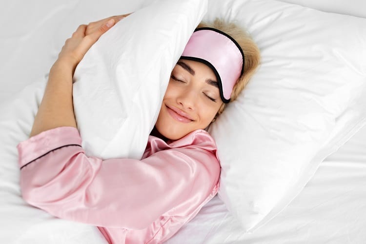 a happy woman under her duvet not using her central heating to keep warm