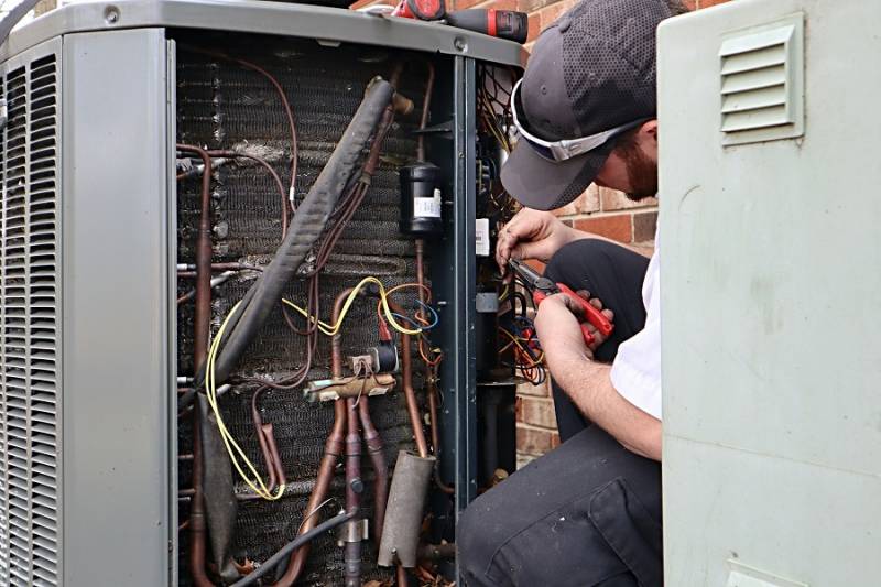 Plumber performing service repair work on an air source heat pump