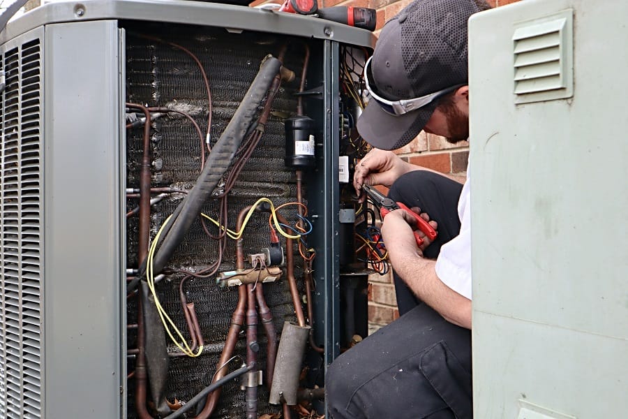 Plumber doing repair work on heat pump Plumber performing service repair work on an air source heat pump