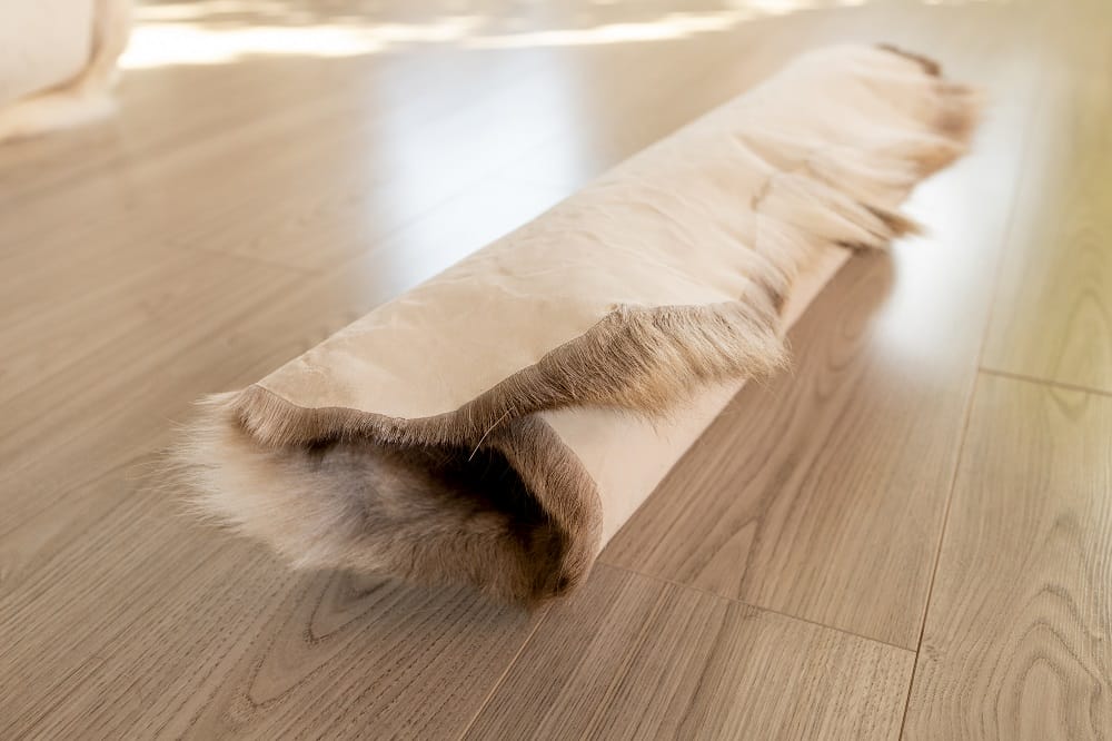 Draught excluder insulation material rolled up on laminate floor