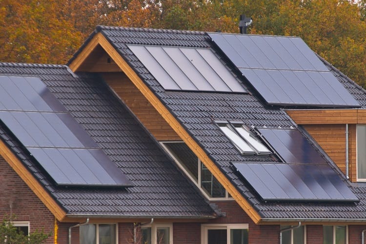 Modern home with multiple solar panels on black roof Modern home with multiple solar panels on black roof