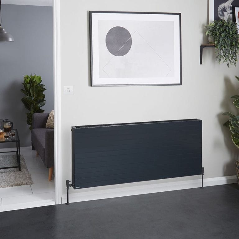 Stelrad Vita Deco anthracite horizontal convector radiator on white wall beneath framed artwork nearby shelf with houseplant