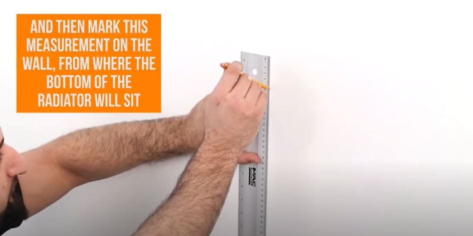 hand marking a line on a wall with a ruler
