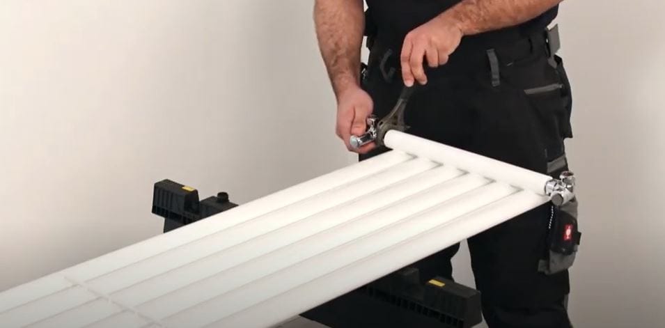 man inserting radiator valves to a vertical radiator