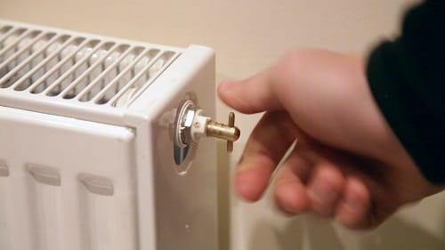 a man turning a radiator bleed key in a radiator bleed valve