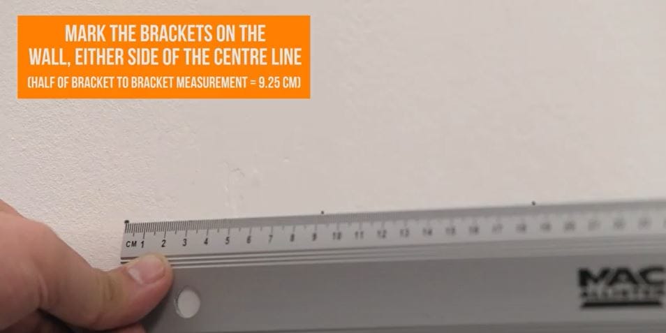 hand holding a ruler on a wall