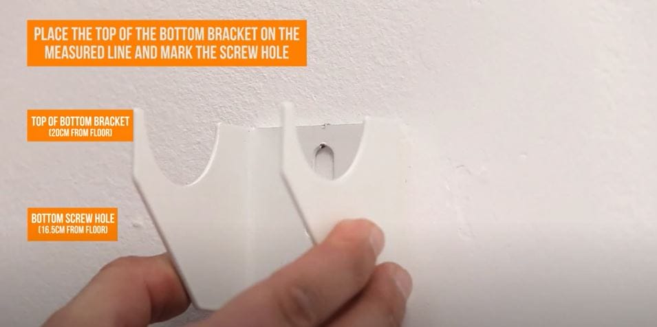 hand holding a radiator bracket on a wall