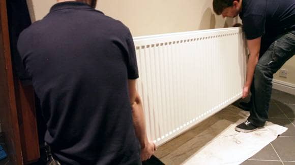 two men lifting a radiator off the wall