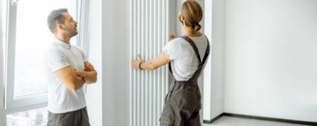 a plumber installing a white vertical column radiator for a customer