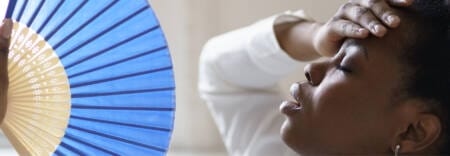 Woman using a blue fan to cool herself down