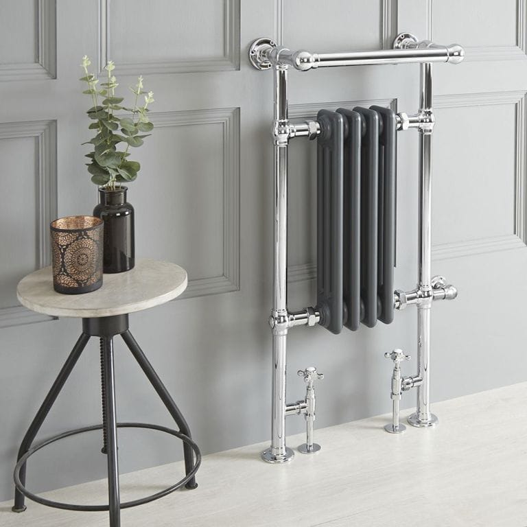 Milano Elizabeth anthracite traditional dual fuel heated towel rail on grey wall nearby small table with candle and vase