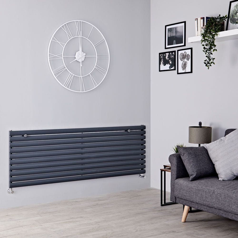 Milano Aruba anthracite horizontal designer radiator on white wall beneath large clock and nearby artwork and shelving and grey settee