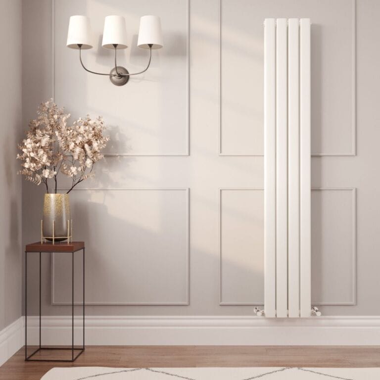 Milano Alpha vertical flat double panel designer radiator on light wall nearby table with gold vase and artificial plant beneath triple light fitting