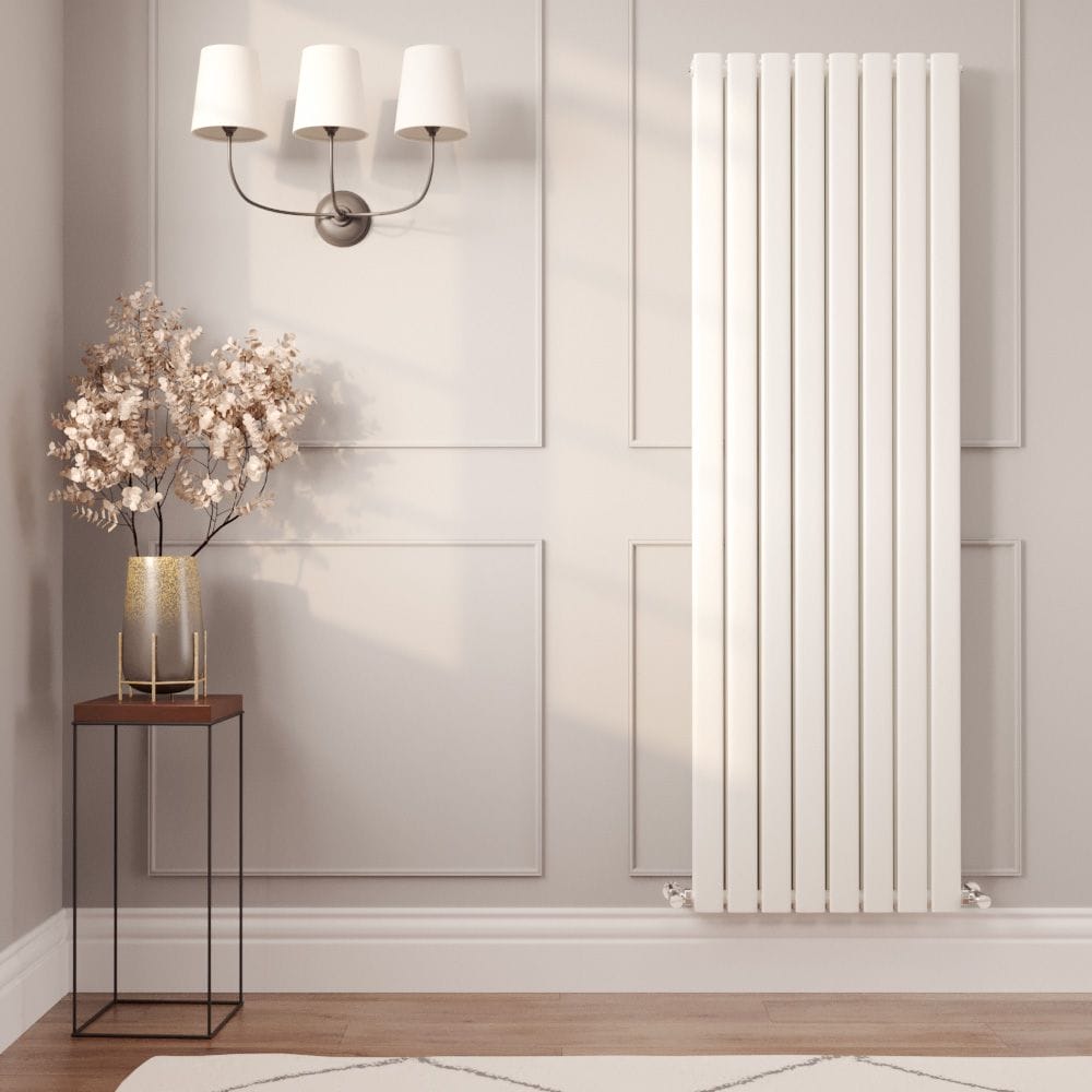 Milano Alpha white vertical flat panel designer radiator on light wall nearby table with vase and artificial houseplant beneath triple light fitting
