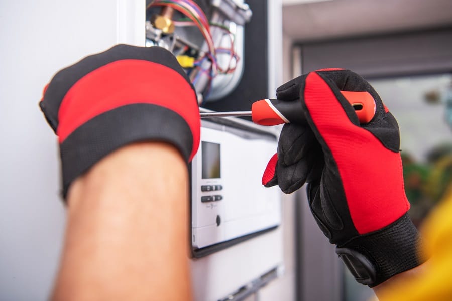 Technician repairing gas heater device Technician in gloves repairing gas boiler with screwdriver